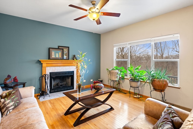 living room featuring plenty of natural light, a fireplace, baseboards, and a ceiling fan