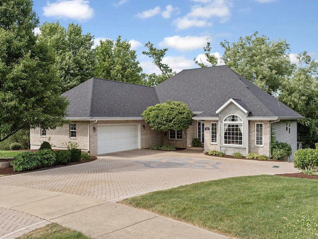 single story home featuring a garage, roof with shingles, brick siding, and decorative driveway