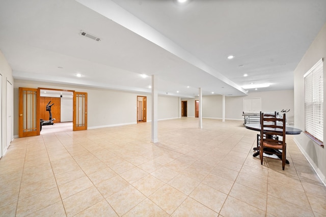 finished below grade area with light tile patterned floors, baseboards, visible vents, and recessed lighting