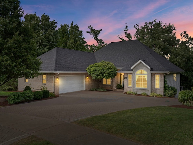 single story home featuring brick siding, a shingled roof, driveway, and an attached garage