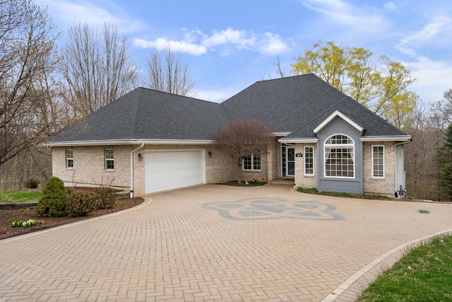 single story home with a garage, brick siding, decorative driveway, and a shingled roof