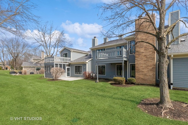 rear view of house with a balcony, a chimney, a sunroom, and a lawn