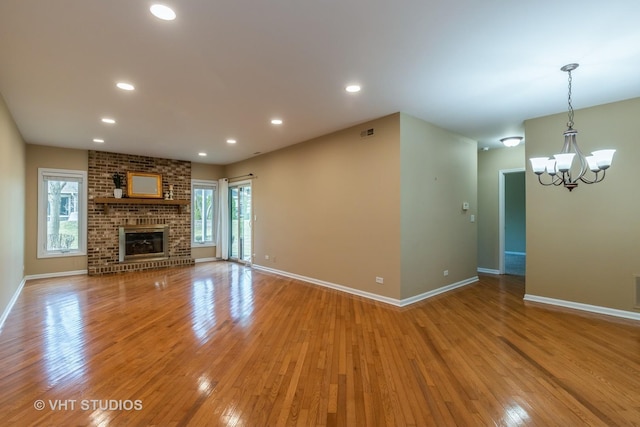 unfurnished living room featuring an inviting chandelier, baseboards, light wood-style floors, and recessed lighting