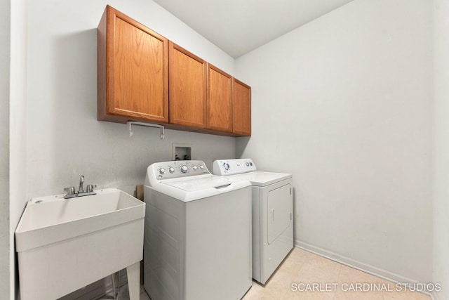 laundry room with a sink, cabinet space, baseboards, and separate washer and dryer