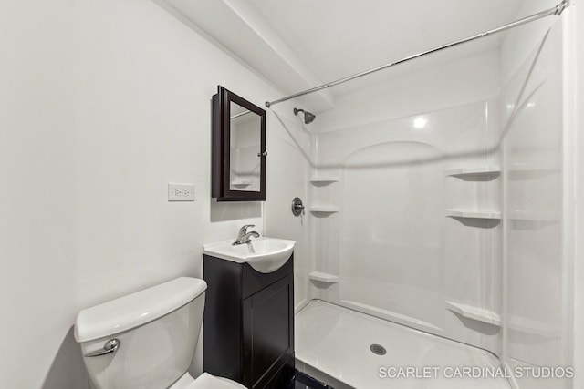 bathroom featuring toilet, a shower, and vanity