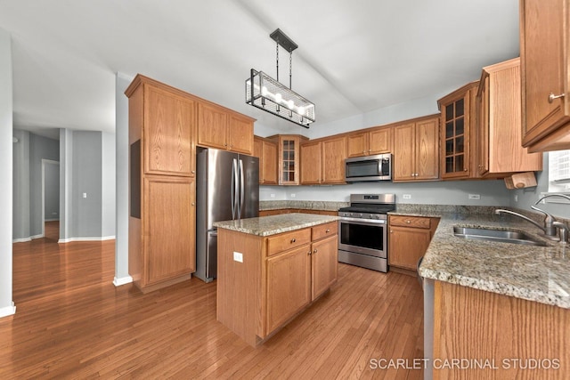kitchen featuring a kitchen island, a sink, appliances with stainless steel finishes, and light stone counters