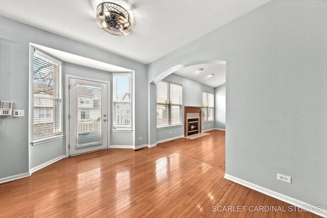 entrance foyer with hardwood / wood-style floors, arched walkways, and baseboards