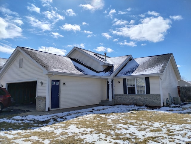view of front of home with an attached garage, a shingled roof, cooling unit, and brick siding