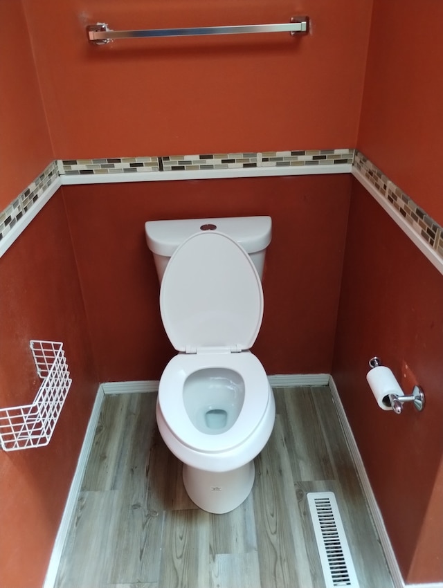 bathroom featuring baseboards, visible vents, wood finished floors, and toilet