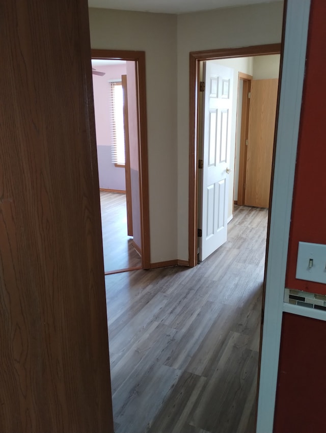 hall with baseboards and wood finished floors