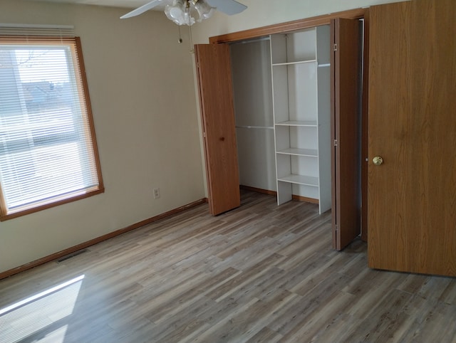 unfurnished bedroom featuring a closet, a ceiling fan, light wood-type flooring, baseboards, and visible vents