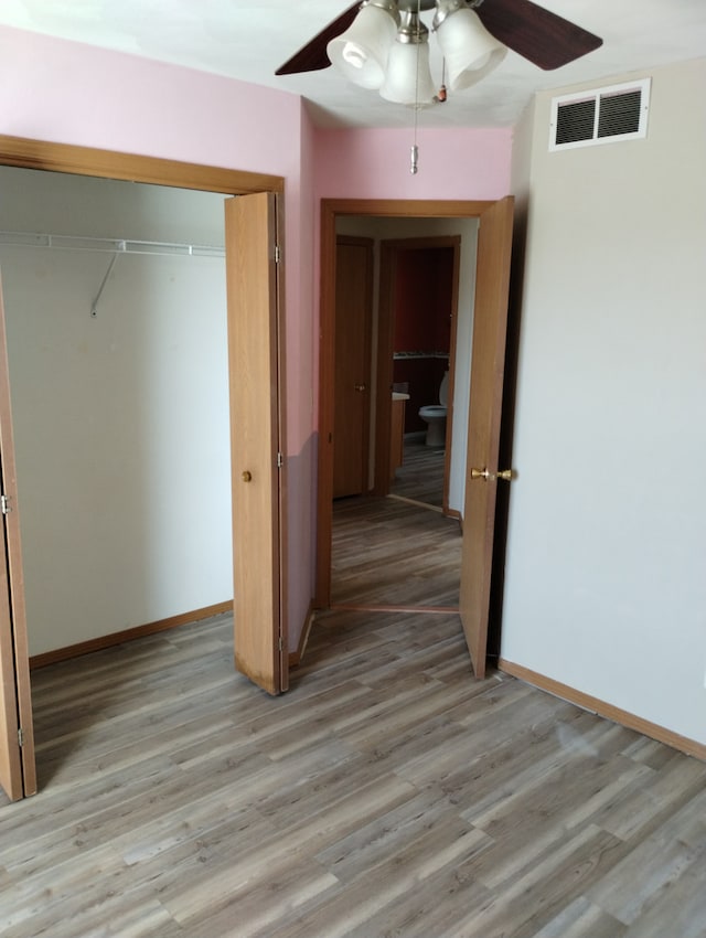 unfurnished bedroom with a closet, baseboards, light wood-style flooring, and visible vents