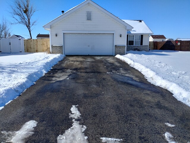 view of front of property featuring driveway, a gate, an attached garage, and fence