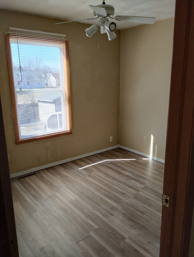 unfurnished room featuring baseboards, wood finished floors, and ceiling fan