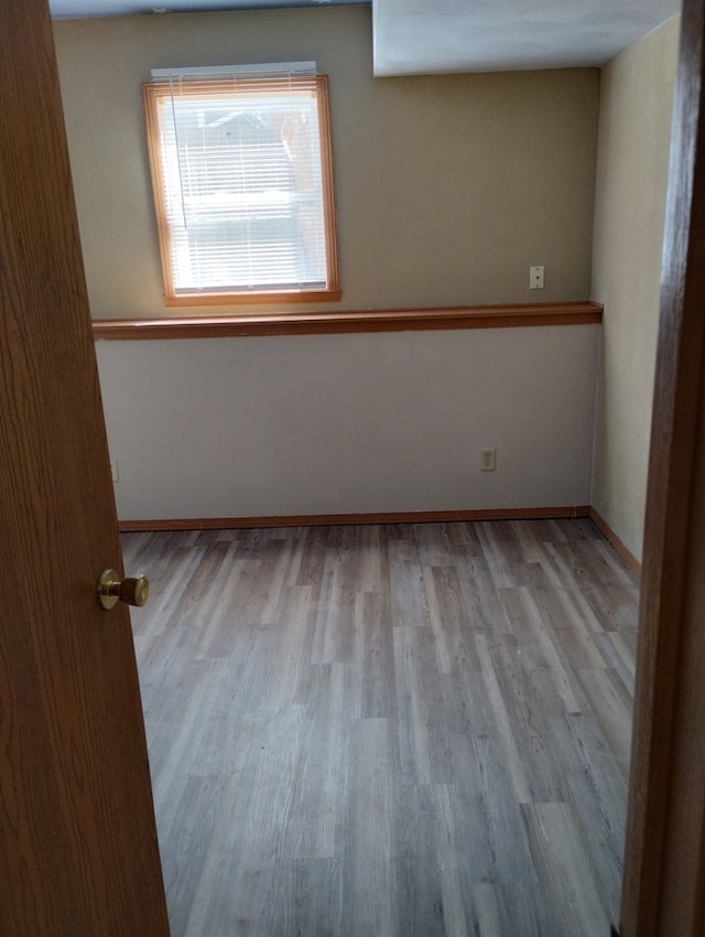 spare room featuring baseboards and wood finished floors
