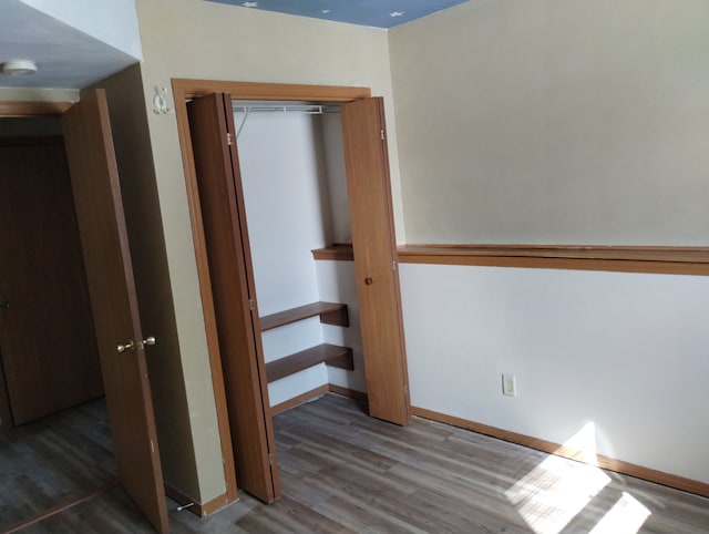 unfurnished bedroom with a closet, baseboards, and wood finished floors