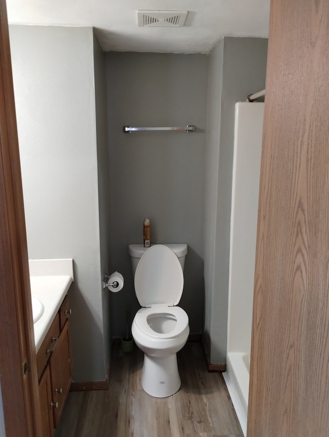 bathroom featuring visible vents, wood finished floors, toilet, and walk in shower