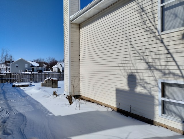 view of snowy exterior with a residential view and fence