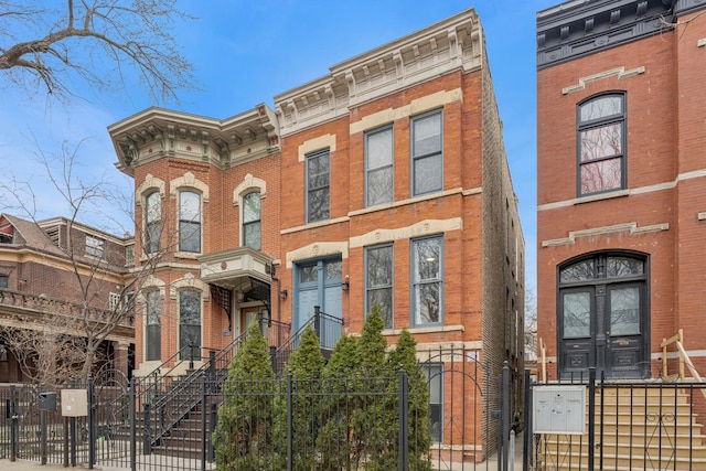 italianate-style house featuring a gate, a fenced front yard, and brick siding