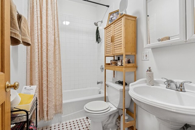 bathroom featuring toilet, a sink, and shower / bath combo with shower curtain