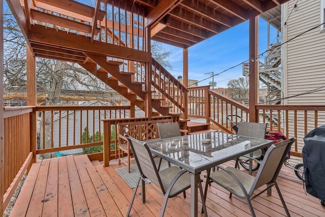 wooden deck with outdoor dining area, stairs, and a grill