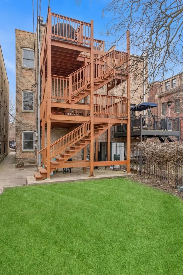 rear view of property featuring fence, a patio, stairs, a deck, and a yard