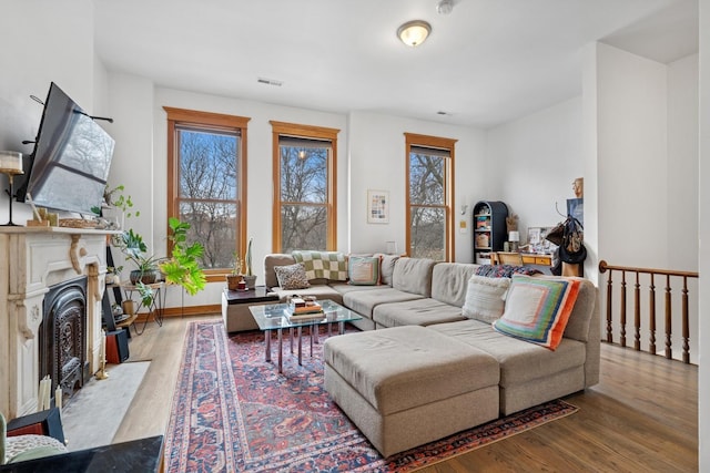 living room with baseboards, visible vents, wood finished floors, and a high end fireplace