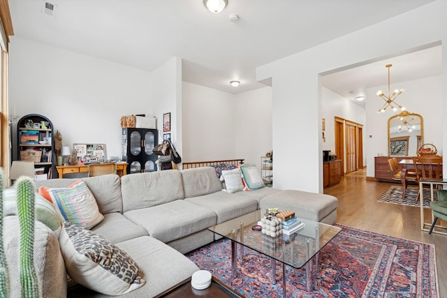 living area featuring visible vents, a notable chandelier, and wood finished floors