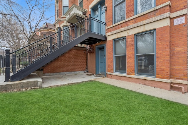 entrance to property with brick siding and a yard
