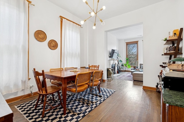 dining area featuring baseboards, wood finished floors, and a chandelier