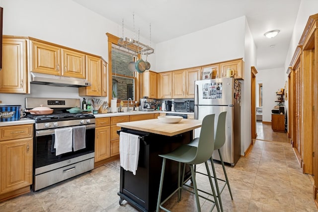 kitchen featuring a towering ceiling, a kitchen bar, stainless steel appliances, butcher block counters, and under cabinet range hood