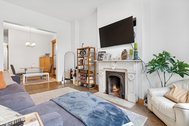living area featuring a fireplace, a chandelier, and wood finished floors