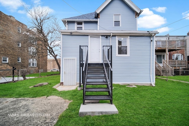 rear view of property featuring a lawn and fence