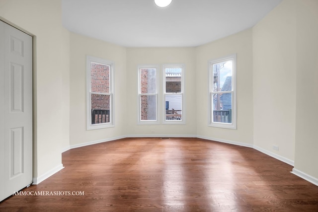 spare room with baseboards and wood finished floors