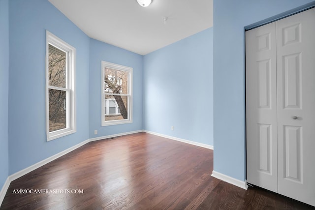 spare room featuring dark wood-style floors and baseboards