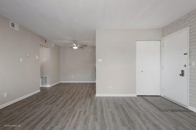 empty room with visible vents, wood finished floors, baseboards, and ceiling fan