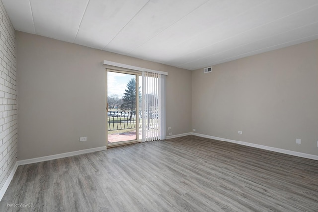 empty room with visible vents, baseboards, and wood finished floors