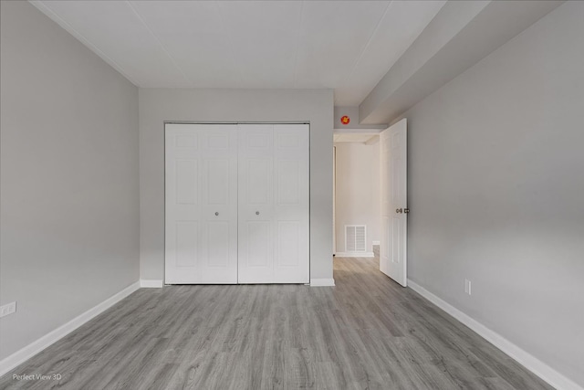 unfurnished bedroom with a closet, visible vents, baseboards, and wood finished floors