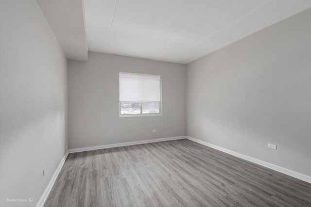 spare room with baseboards and wood finished floors