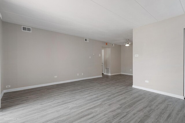 spare room with ceiling fan, visible vents, baseboards, and wood finished floors