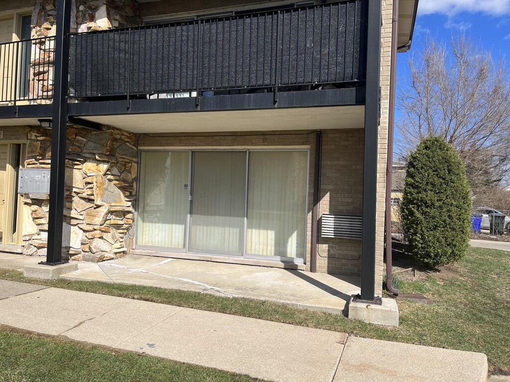 doorway to property featuring brick siding, stone siding, and a balcony