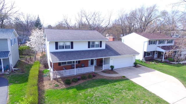traditional-style house featuring roof with shingles, a front lawn, driveway, a porch, and a garage