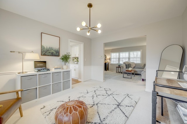 interior space featuring a wainscoted wall, a notable chandelier, and light colored carpet