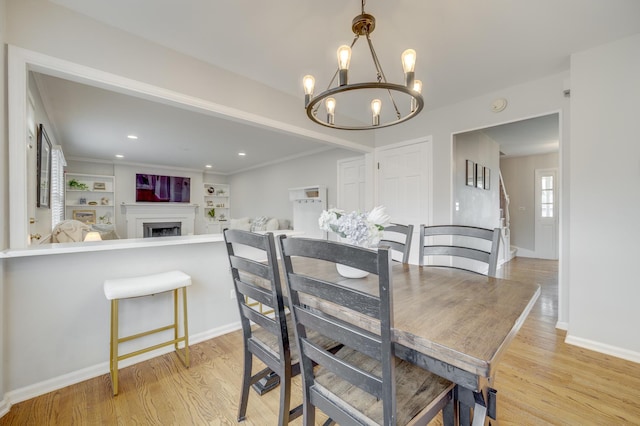dining space with baseboards, a notable chandelier, light wood finished floors, and a fireplace