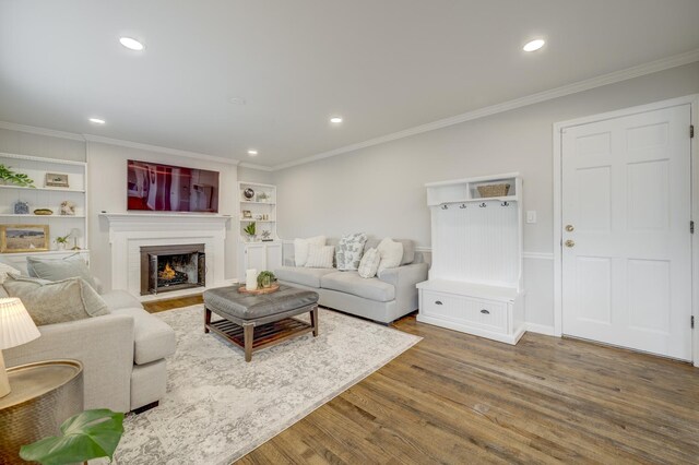 living room featuring recessed lighting, wood finished floors, a lit fireplace, and ornamental molding