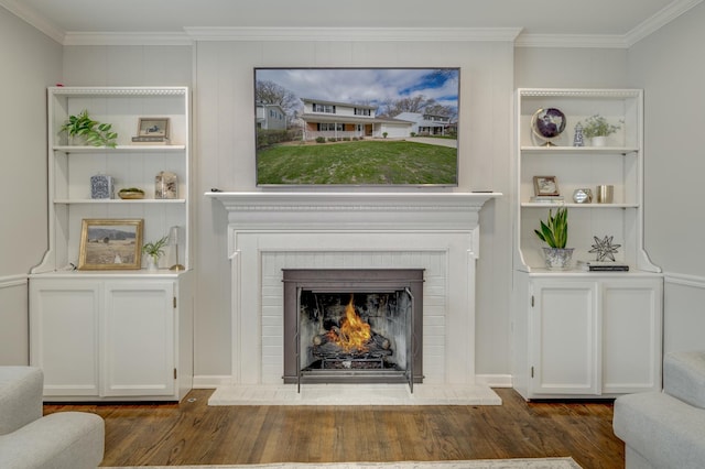 living area with a brick fireplace, dark wood-style floors, built in features, and ornamental molding