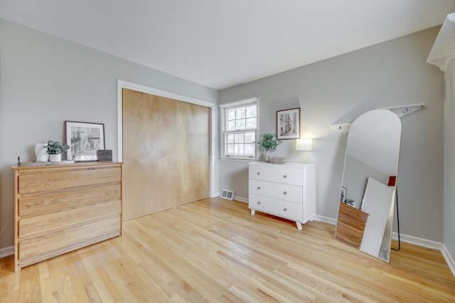 bedroom featuring light wood-style floors, baseboards, visible vents, and a closet