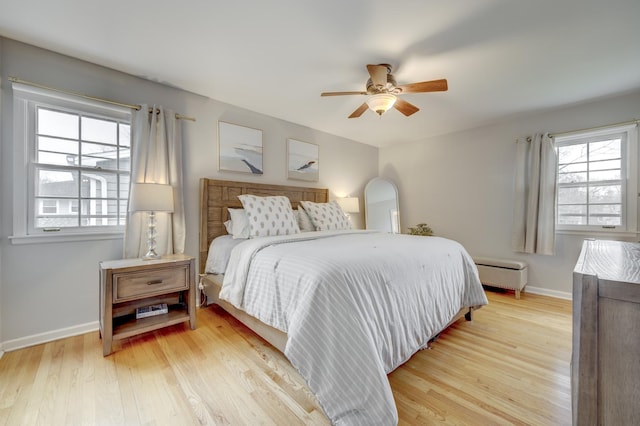 bedroom featuring light wood finished floors, a ceiling fan, and baseboards