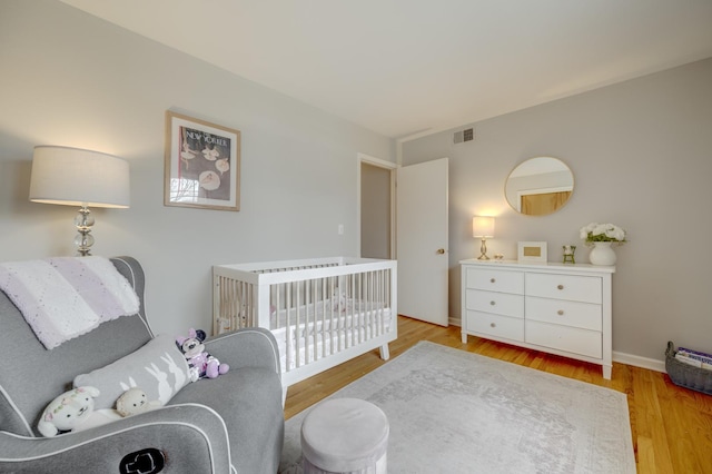 bedroom featuring baseboards, light wood-style floors, and visible vents
