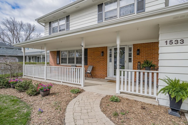 doorway to property featuring brick siding and covered porch